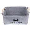 Gray felt pet toy storage basket with wooden handles.