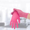 A hand wearing a pink nitrile disposable glove is shown interacting with a surface.