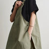 A person wearing a olive green waterproof work apron over a black shirt.