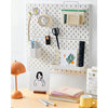A white wall-mounted pegboard organizer with hooks and storage boxes displaying various tools and stationery.
