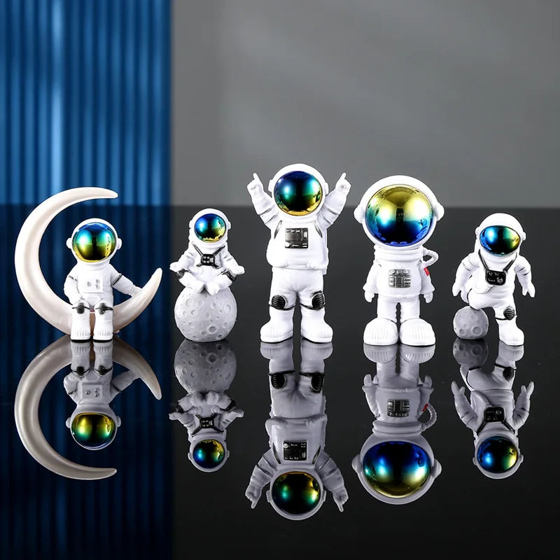 A collection of handcrafted astronaut figurine resin spacemen desk decor displayed on a dark surface.