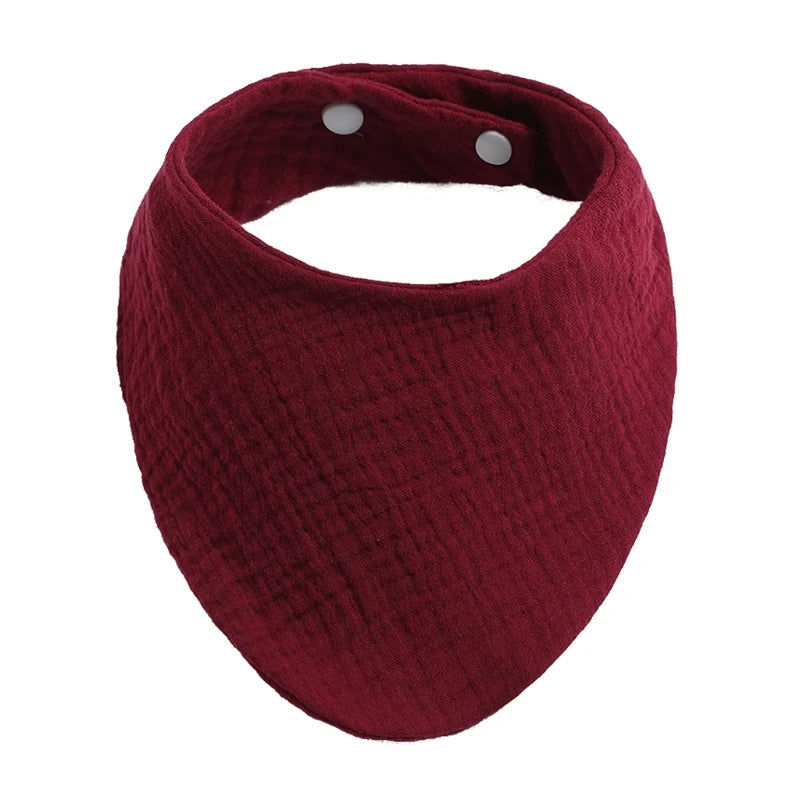 A deep maroon organic cotton muslin baby bib with an absorbent bandana and a gathered design.