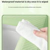 A hand is wiping a white, absorbent material on a light green toilet seat cover.