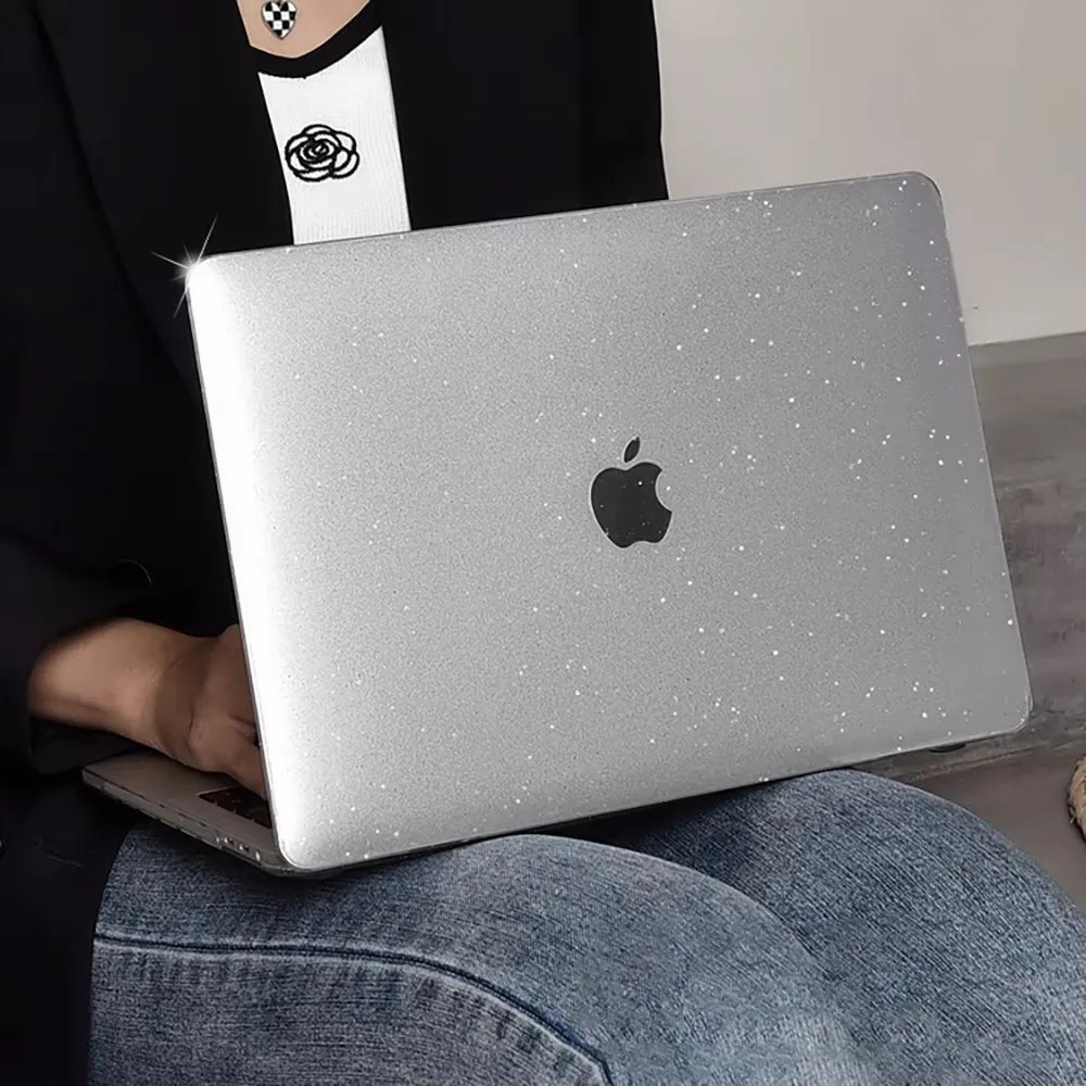 A person holds a silver laptop with a black Apple logo on it, resting on their lap.