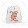 A beige drawstring storage bag featuring a cute cartoon capybara illustration with the text Don't Worry Be Cappy
