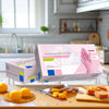 Box of disposable pink nitrile gloves with a pink and white design placed on a wooden table.
