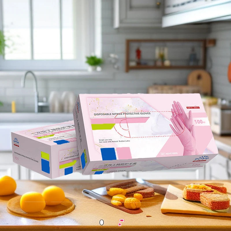 Box of disposable pink nitrile gloves with a pink and white design placed on a wooden table.