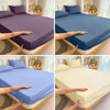 Hands demonstrate the fit and texture of a solid blue fitted bed sheet on a bed frame.