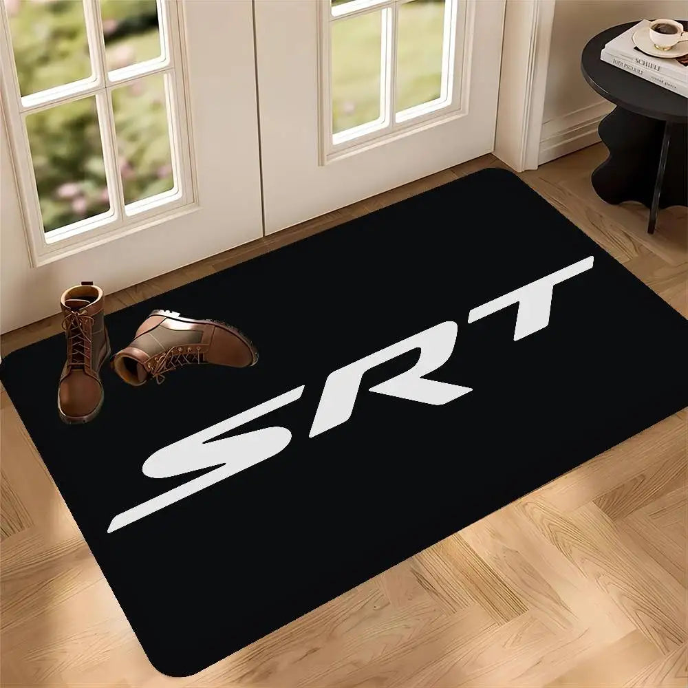 A black doormat featuring white SRT logo placed on a light wooden floor near a window.