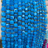 A close-up of strands of bright blue natural stone square faceted beads for jewelry making