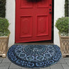 A red painted door with paneling and a blue patterned stone tile doormat in front of it.