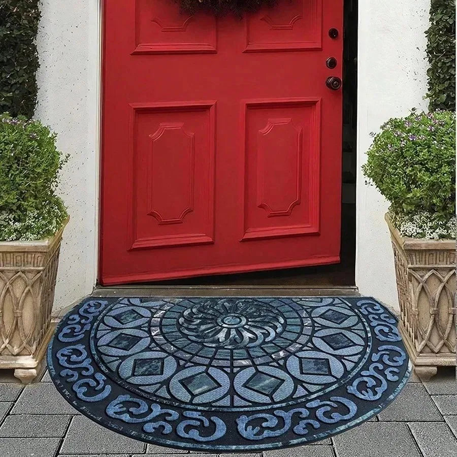 A red painted door with paneling and a blue patterned stone tile doormat in front of it.