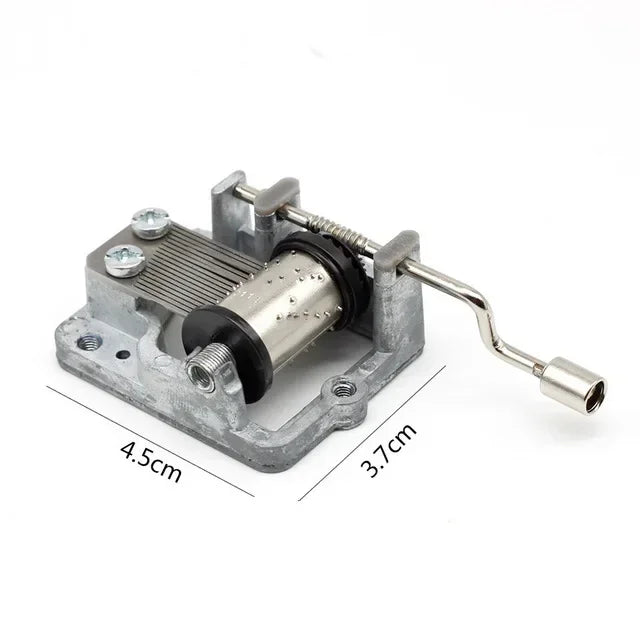 A vintage hand-crank music box mechanism with a silver metal frame and wooden cylinder.
