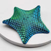 A teal and blue 3D printed articulated starfish fidget toy resting on a white surface.