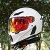A white full-face motorcycle helmet with an orange tinted visor is shown outdoors.