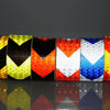 A row of high-visibility reflective safety tape rolls displaying various colors including yellow, green, black, red, and blue