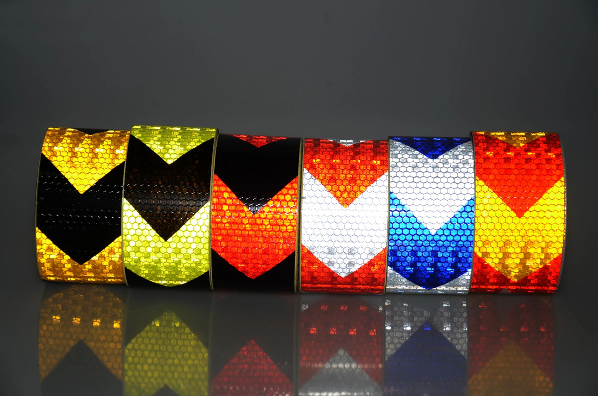 A row of high-visibility reflective safety tape rolls displaying various colors including yellow, green, black, red, and blue