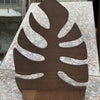 A dark brown wooden wall-mounted storage rack with a leaf design set against a light granite surface.