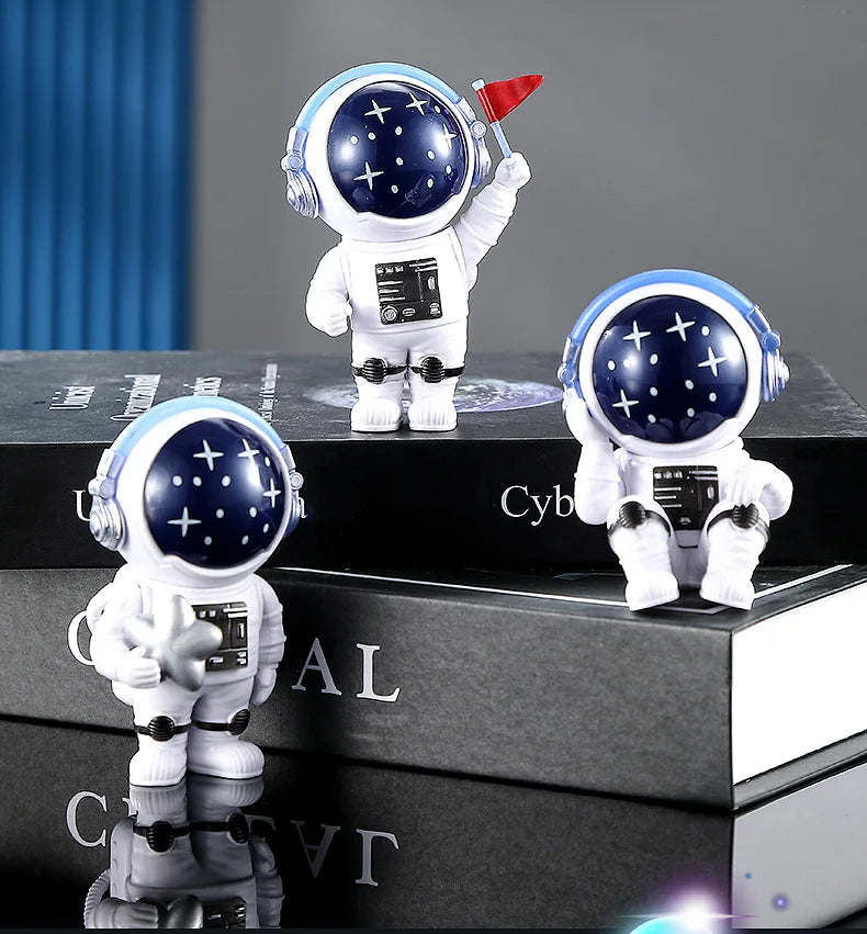 A white astronaut figurine with a blue helmet and black suit is displayed on stacked dark boxes.