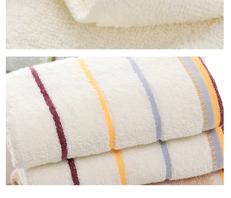 A stack of white bath towels with stripes in shades of yellow, purple, and gray.