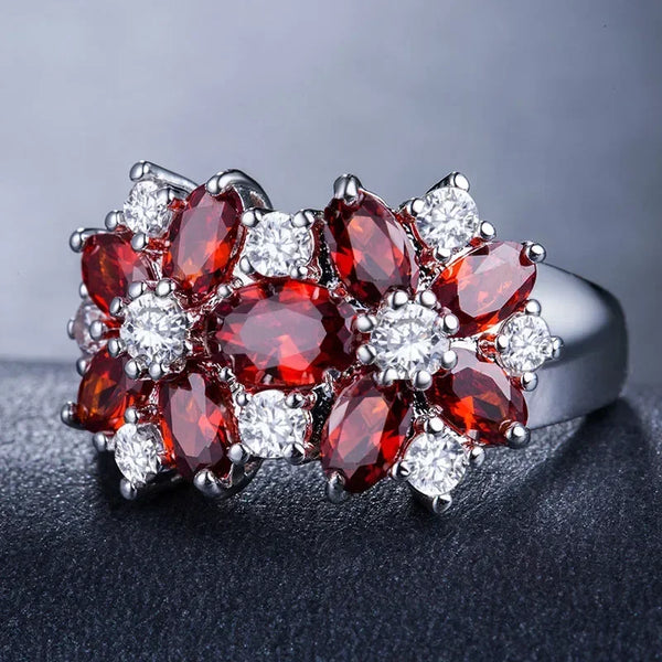 Anillo de cóctel floral con un clúster de piedras preciosas rojas y circonitas cúbicas claras en plata.