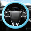 A close-up view of a black steering wheel with a light blue silicone cover installed in a car interior.
