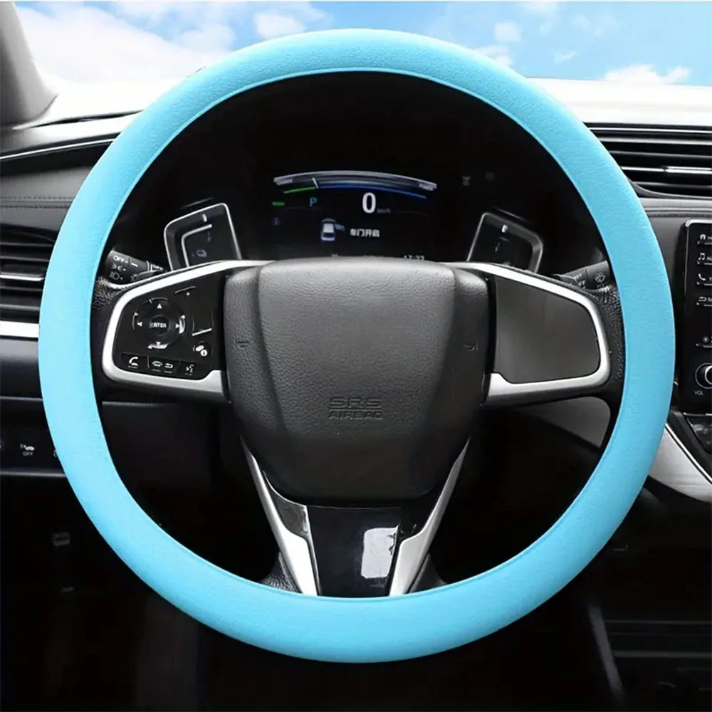 A close-up view of a black steering wheel with a light blue silicone cover installed in a car interior.
