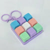 A purple keychain fidget toy featuring colorful square tactile clicking buttons in shades of blue, pink, and green.