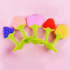A set of silicone baby teethers shaped like strawberries in pink, red, and yellow colors.