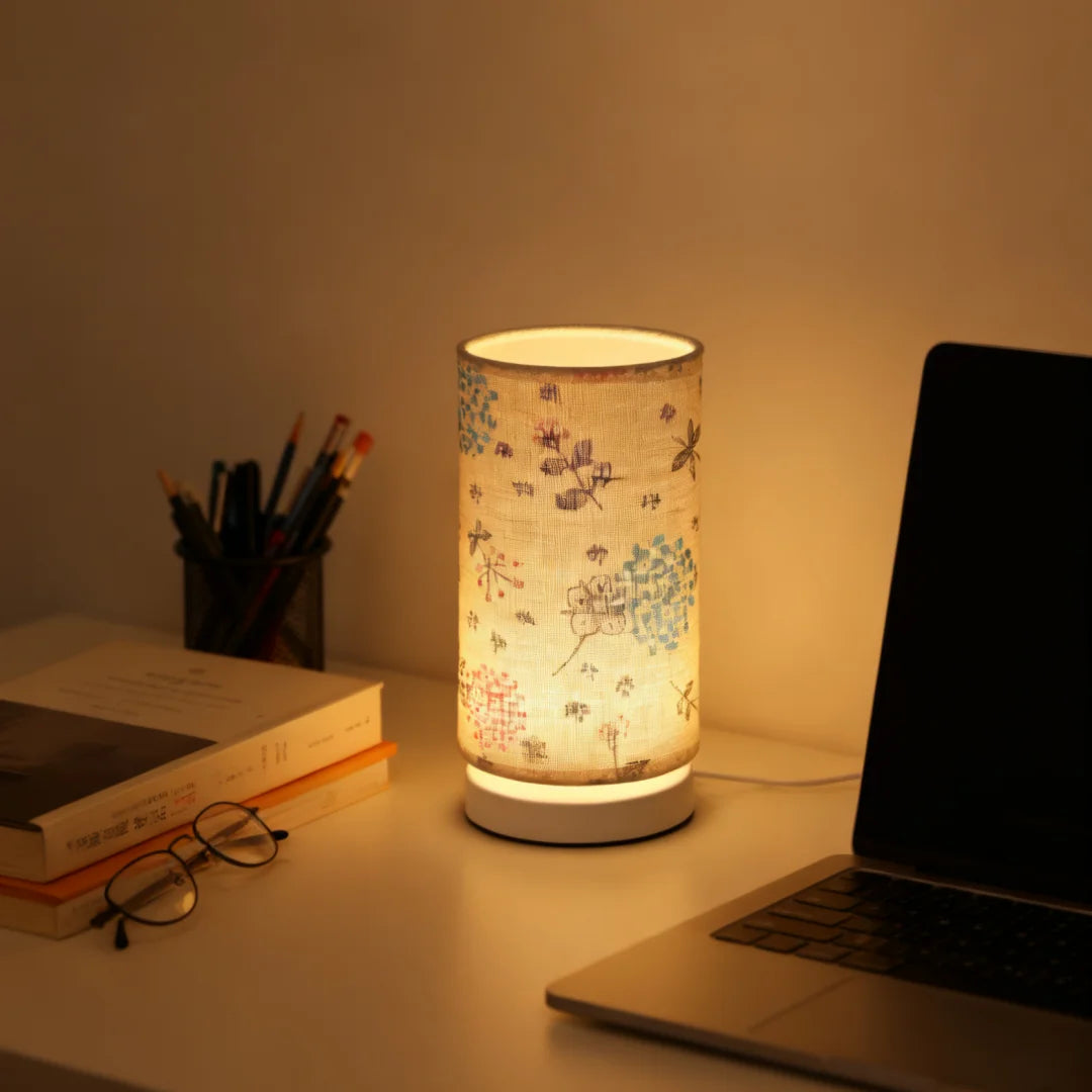 A Nordic retro USB table lamp with a fabric shade illuminates a workspace next to a laptop and pencils.