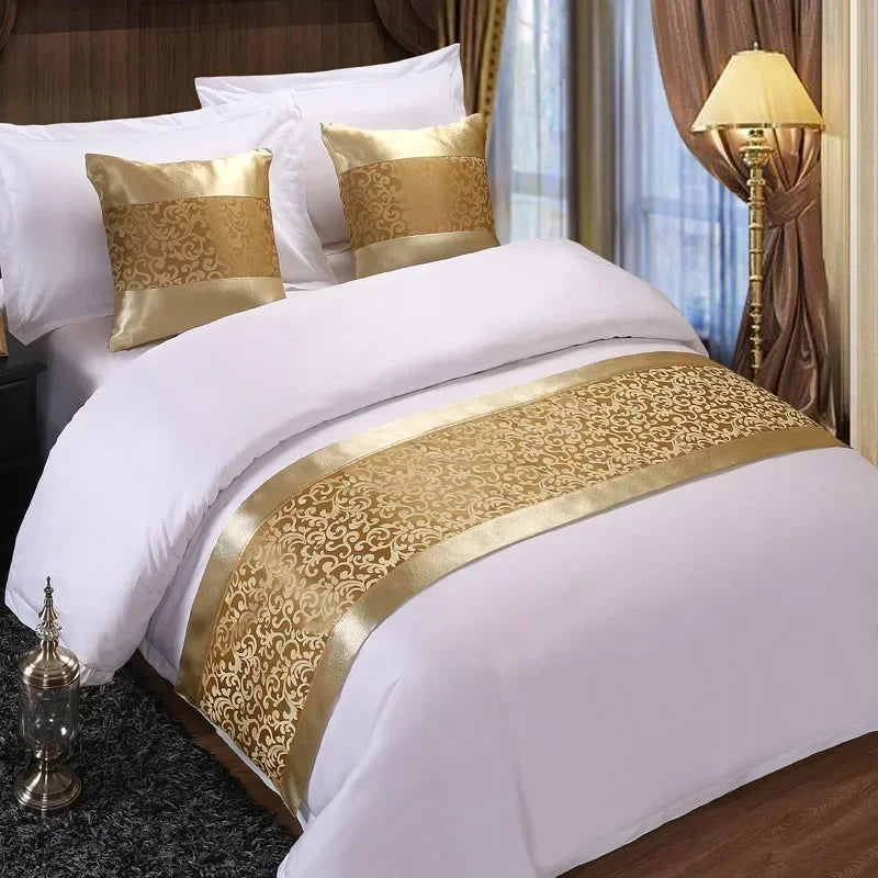 White bedding with gold patterned bed runner and pillows in a bedroom setting
