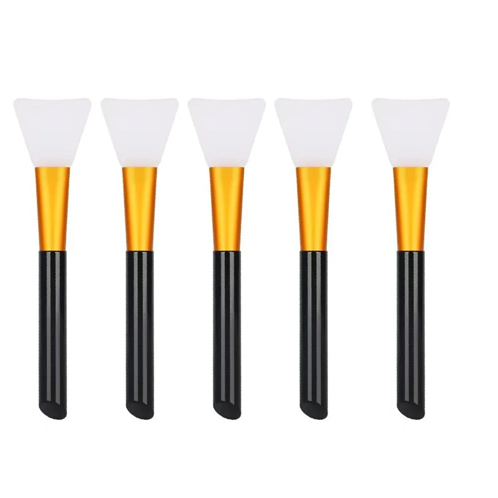 Five silicone facial mask brushes with white heads and gold bases and black handles