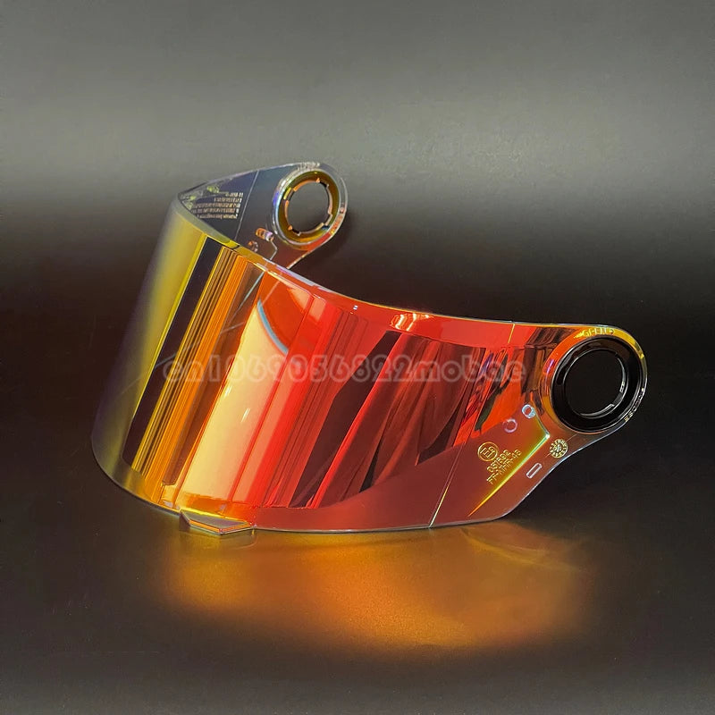 A clear replacement motorcycle helmet visor reflecting warm orange and red light on a dark surface.