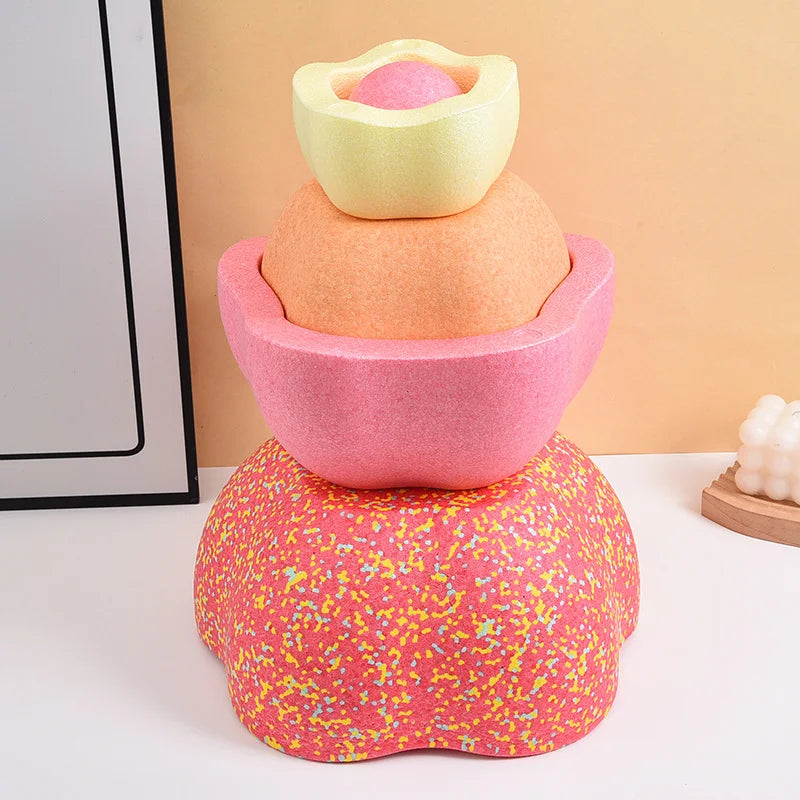 A stack of three colorful, textured balance stepping stones in pink, orange, and yellow.