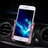 A white smartphone is held in a crystal air vent car phone holder on a black surface.