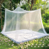 A sheer white lace canopy mosquito net draped over a bed in a lush green garden setting.