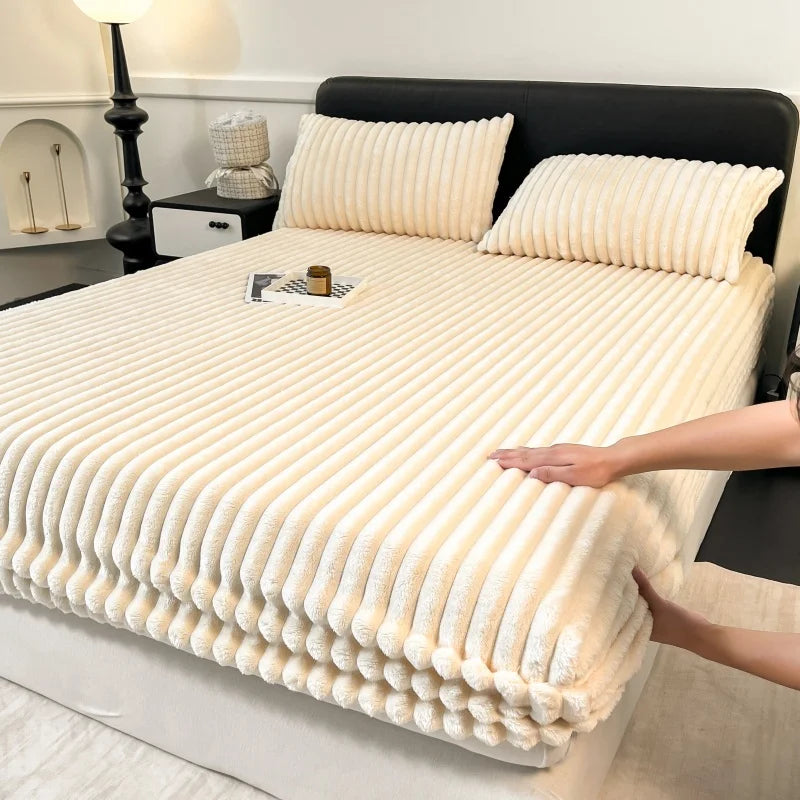 A thick, cream-colored knit fitted bed sheet is displayed on a bed, folded and draped.