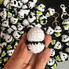 A hand holds a handmade crochet kitten keychain featuring a cute panda and cartoon animal charm.