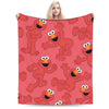 A red flannel throw blanket featuring repeating illustrations of fuzzy orange characters from Sesame Street Friends