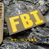 Yellow embroidered patch with the letters FBI on a gray fabric background