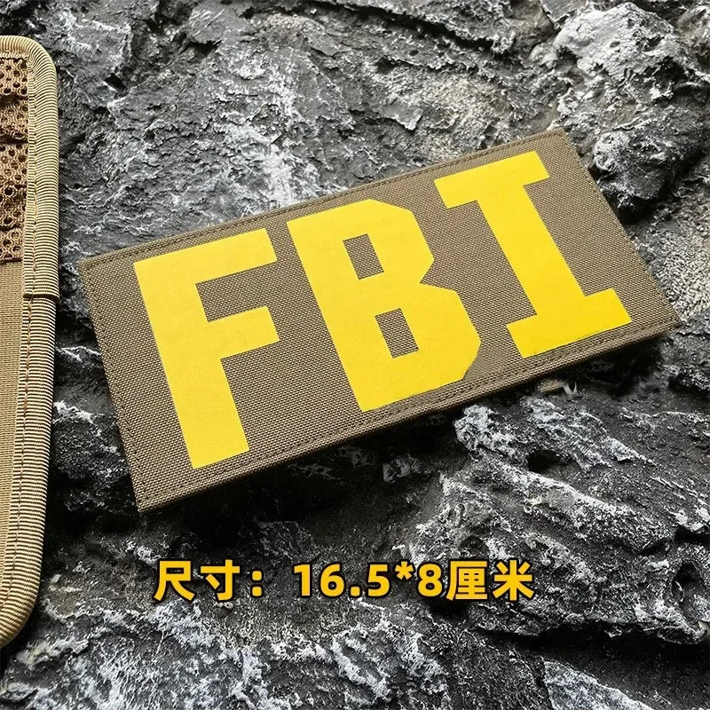Yellow embroidered patch with the letters FBI on a gray fabric background