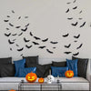 A wall display of lifelike 3D black bat silhouettes with LED glow against a white wall.