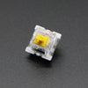 A close-up view of a white plastic mechanical keyboard switch with a yellow housing.