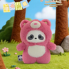 A pink panda plush toy is displayed in a forest setting with tree trunks and green grass.
