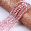 Pink faceted crystal glass spacer beads threaded onto a brown fabric ribbon for jewelry making