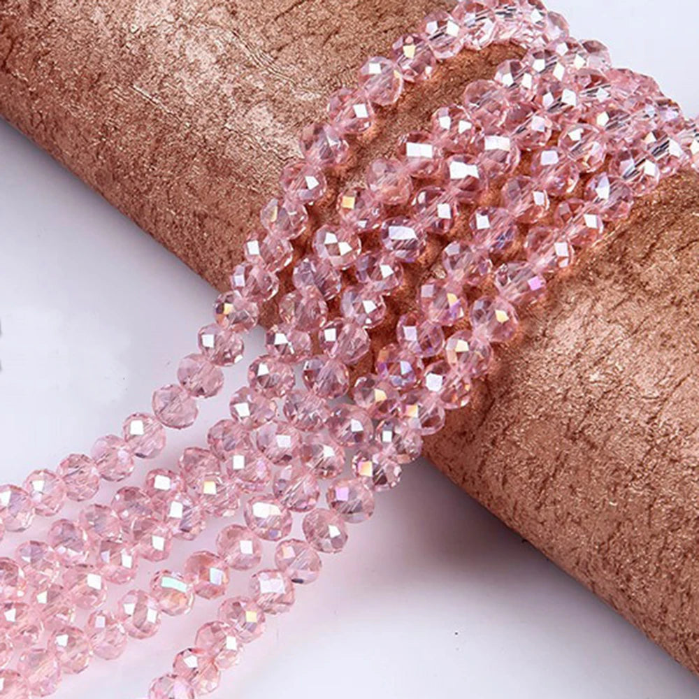 Pink faceted crystal glass spacer beads threaded onto a brown fabric ribbon for jewelry making