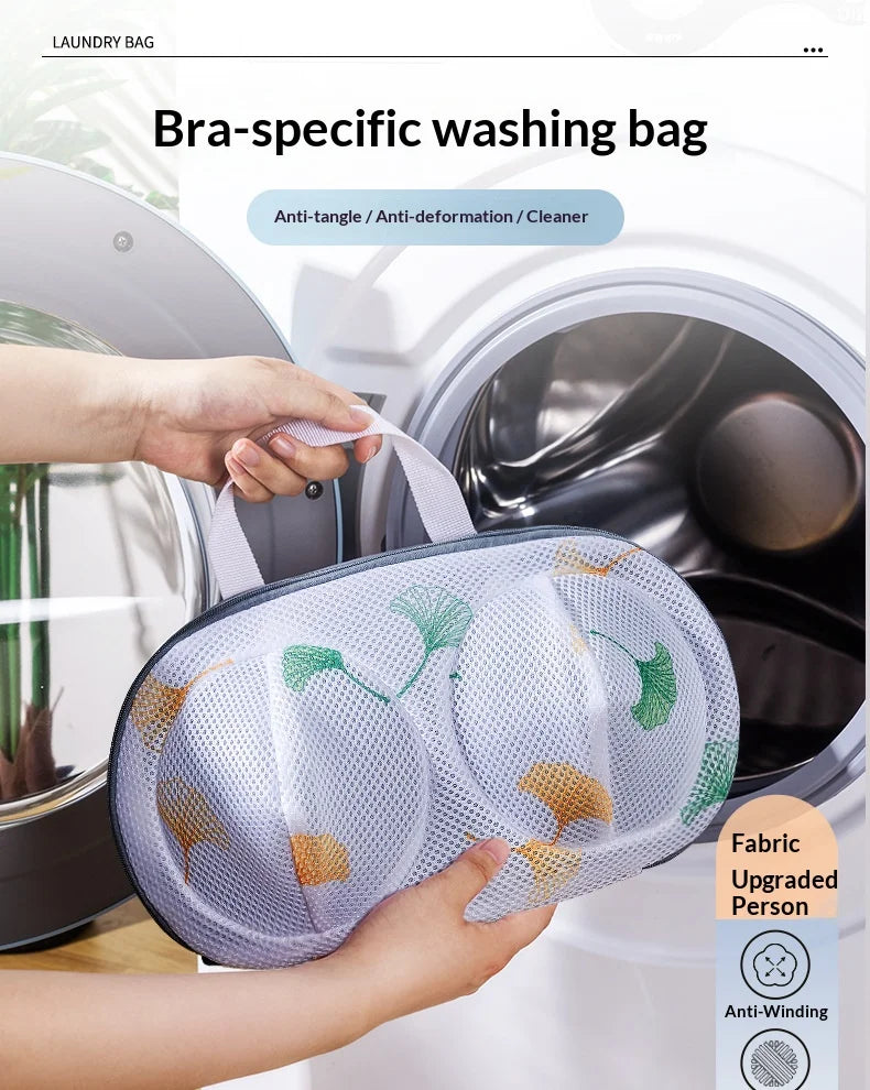 A hand places a mesh bra-specific washing bag into the drum of a washing machine.