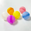 A collection of colorful reusable splash water balloons in yellow, orange, pink, and blue on a white surface.