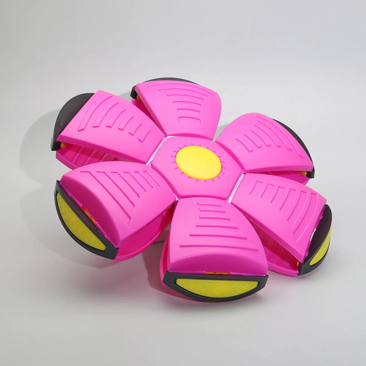 A pink magic flying saucer bouncing ball designed for dogs and kids, featuring ribbed surfaces and a yellow center.