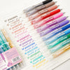 A collection of 12 retractable gel pens in various colors, including pink, red, purple, and green, laid out on a white sheet.